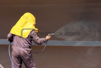 worker painting ship hull using airbrush  
