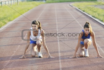 two girls running on athletic race track
