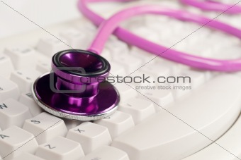 pink stethoscope on white keyboard