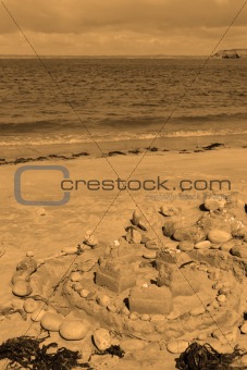 sepia sandcastle and pebbles with seaweed