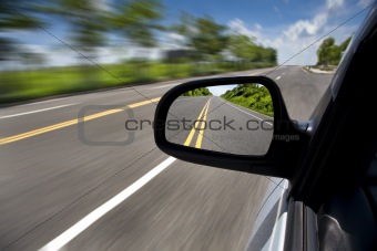 Car driving through the empty road and focus on mirror