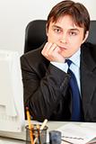Thoughtful modern businessman sitting at office desk
