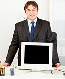 Smiling businessman standing at office desk and showing monitors blank screen
