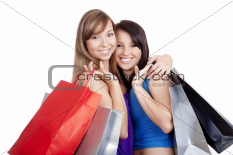 two happy young girls with shopping bags smiling - isolated on white