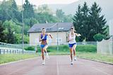 two girls running on athletic race track