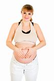 Smiling pregnant woman making heart with her hands on tummy
