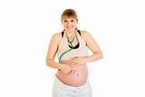 Smiling pregnant woman holding stethoscope on her tummy
