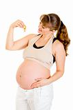 Smiling pregnant woman holding  baby dummy near tummy
