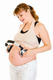 Happy pregnant woman holding headphones on her tummy
