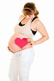 Smiling pregnant woman holding heart near her tummy
