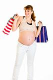 Happy pregnant female holding shopping bags in hands
