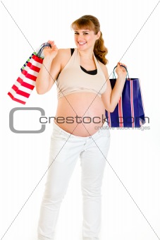 Happy pregnant female holding shopping bags in hands

