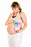  Pregnant woman  holding color paint samples and blowing kiss her belly
