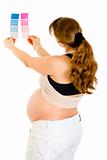 Pregnant woman looking at blue and pink paint samples
