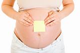 Pregnant woman with blank sticky note on her tummy. Close-up.
