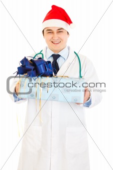 Smiling medical doctor in Santa hat holding present in hands 
