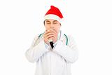 Medical doctor in Santa hat enjoying cup of hot coffee
