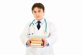 Smiling  doctor holding several medical books in hands
