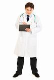 Serious doctor  with stethoscope making notes in medical chart
