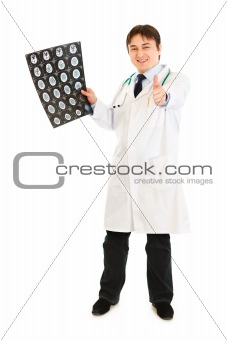 Smiling medical doctor holding tomography and showing thumbs up gesture
