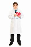 Authoritative medical doctor holding stethoscope on paper heart
