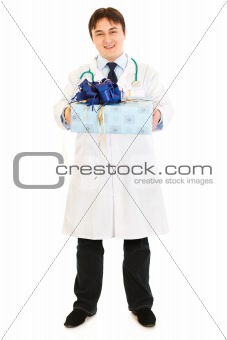 Smiling medical doctor holding present in hands 
