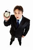 Surprised young businessman holding alarm clock in hand
