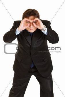Concentrated businessman making binoculars with hands and looking through
