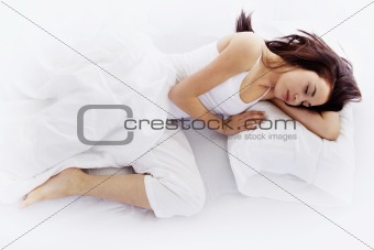 Young woman sleeping on white bed 