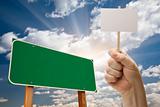 Blank Green Road Sign and Man Holding Poster on Stick Over Blue Sky and Clouds.