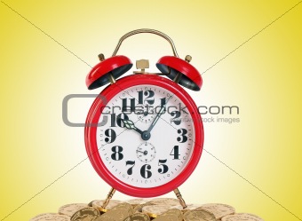Alarm clock with golden coins on yellow background