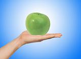 green apple on the hand over blue