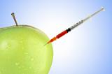 Green apple with a syringe over blue background