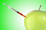 Green apple with a syringe over green background
