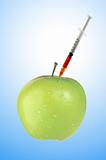 Green apple with a syringe over blue background