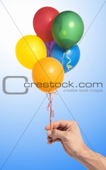 Hand holding colorful air balloons over blue background