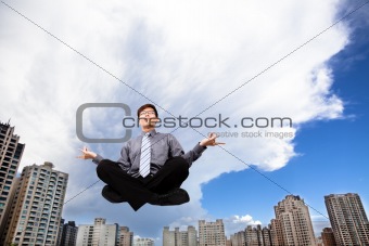 Businessman meditating in the air before modern building