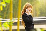 businesswoman talk phone beside trees