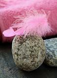 pink feather on the stones and pink towel in the background