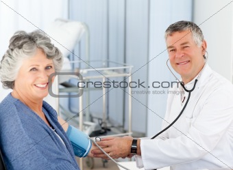 A senior doctor taking the blood pressure of his patient 