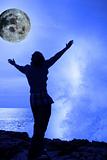 a woman with raised hands facing a wave and full moon on cliff e