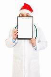 Medical doctor in Santa hat holding blank clipboard
