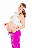 Happy beautiful pregnant woman measuring her belly

