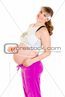 Happy beautiful pregnant woman measuring her belly
