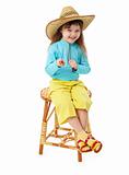 Little girl in straw hat sitting on wooden chair