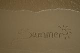 Summer written on sand with water wave