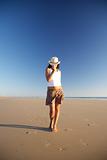 front woman with hat walking at beach