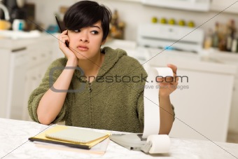 Multi-ethnic Young Woman Agonizing Over Financial Calculations in Her Kitchen.