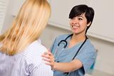 Smiling Attractive Multi-ethnic Young Female Doctor or Nurse Wearing Scrubs and Stethoscope Talking with Patient.