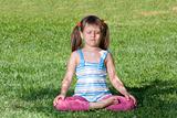 Little child sit and meditate in asana on green grass